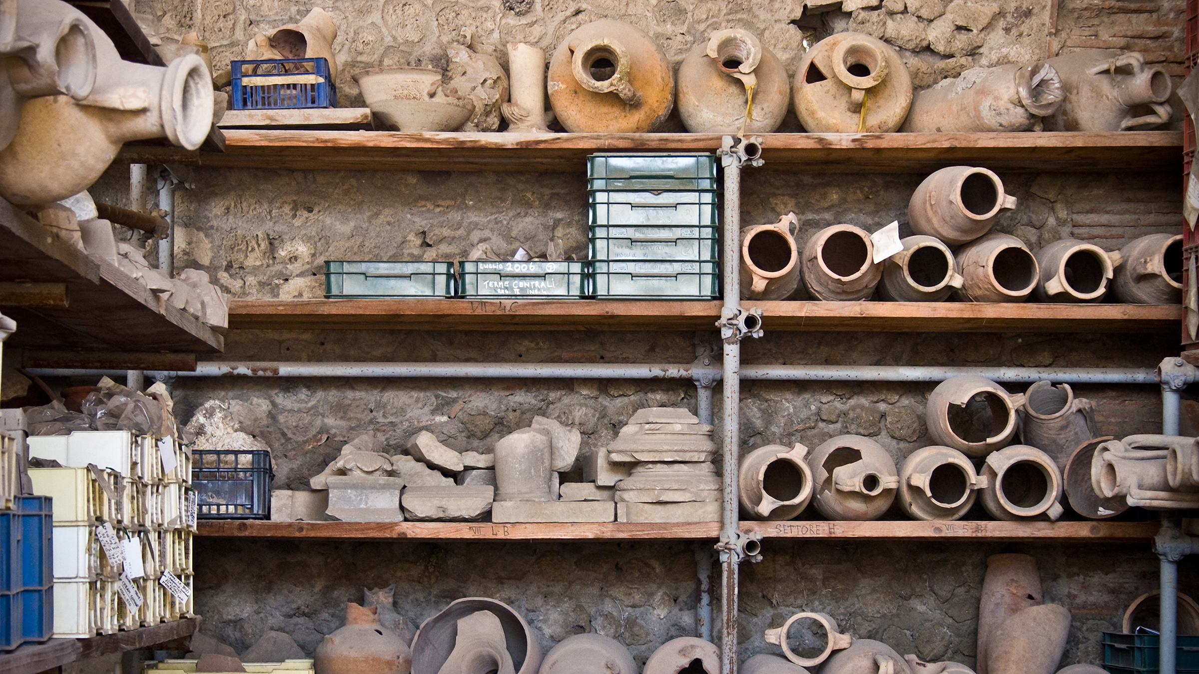 Color photograph of an archeological shelf filled with dusty amphorae and boxes