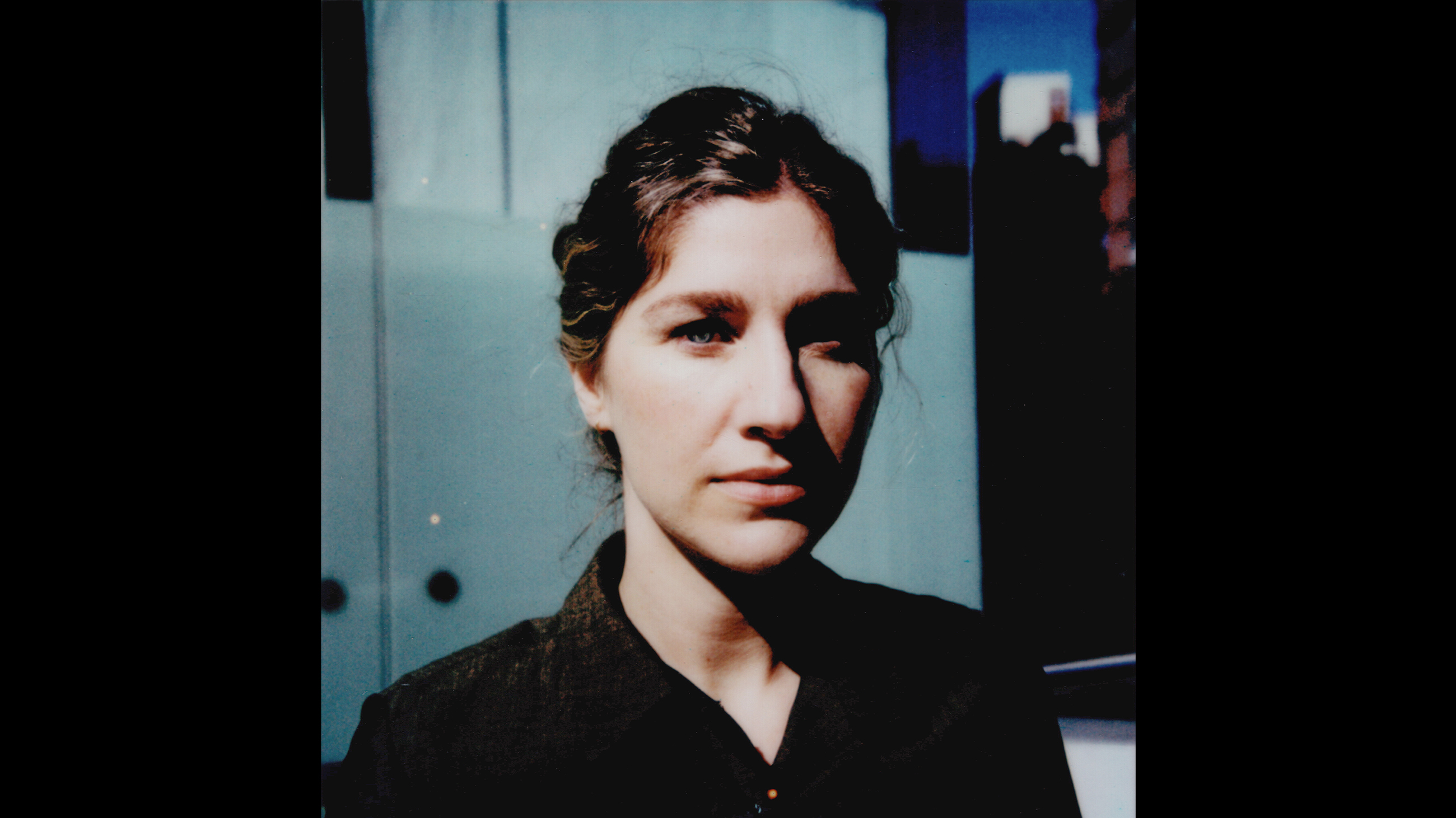 Saturated color photo of the head and shoulders of a light skinned woman looking at the camera