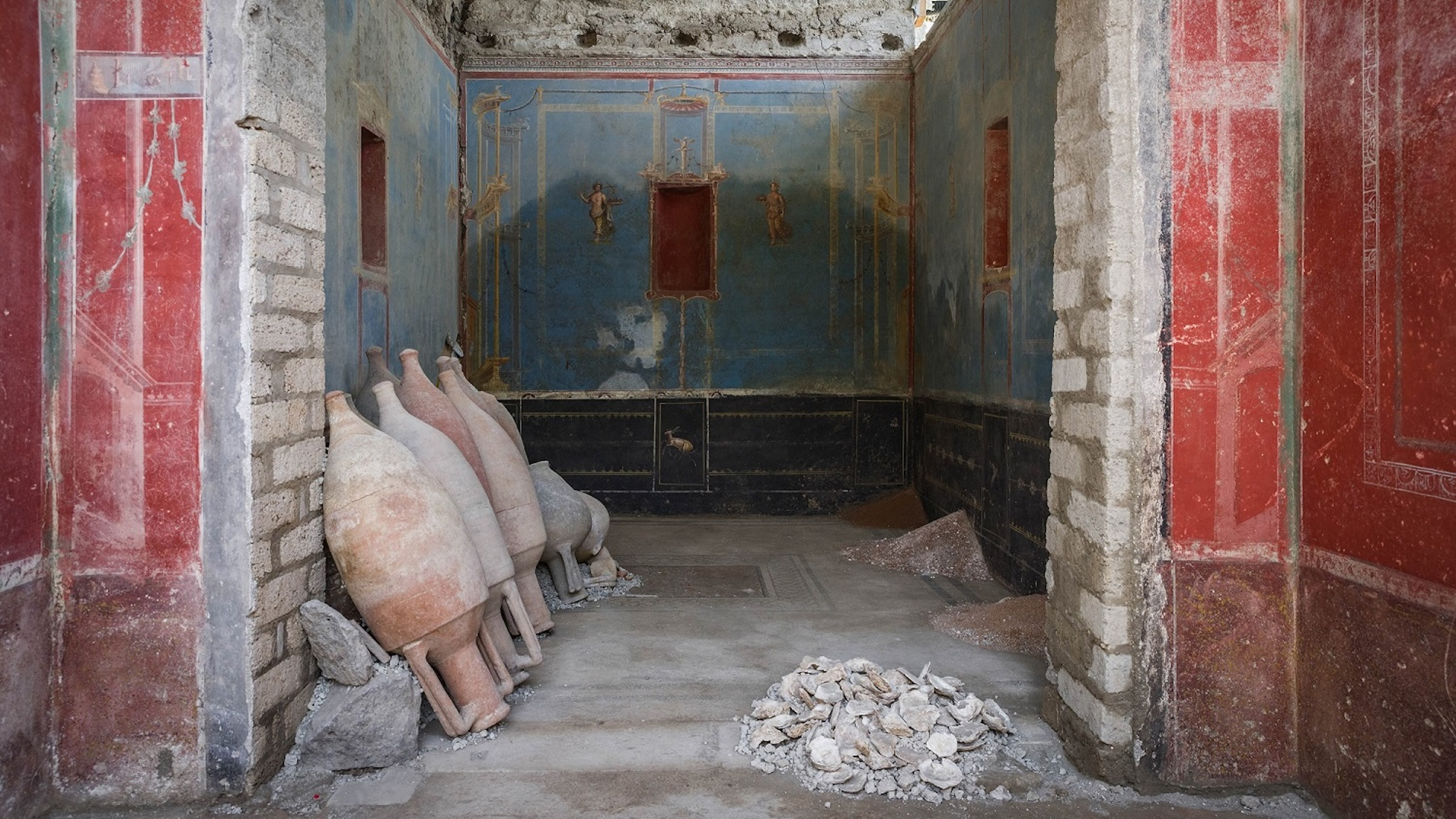 Color photo of the entrance to an ancient Roman room with walls painted red and blue