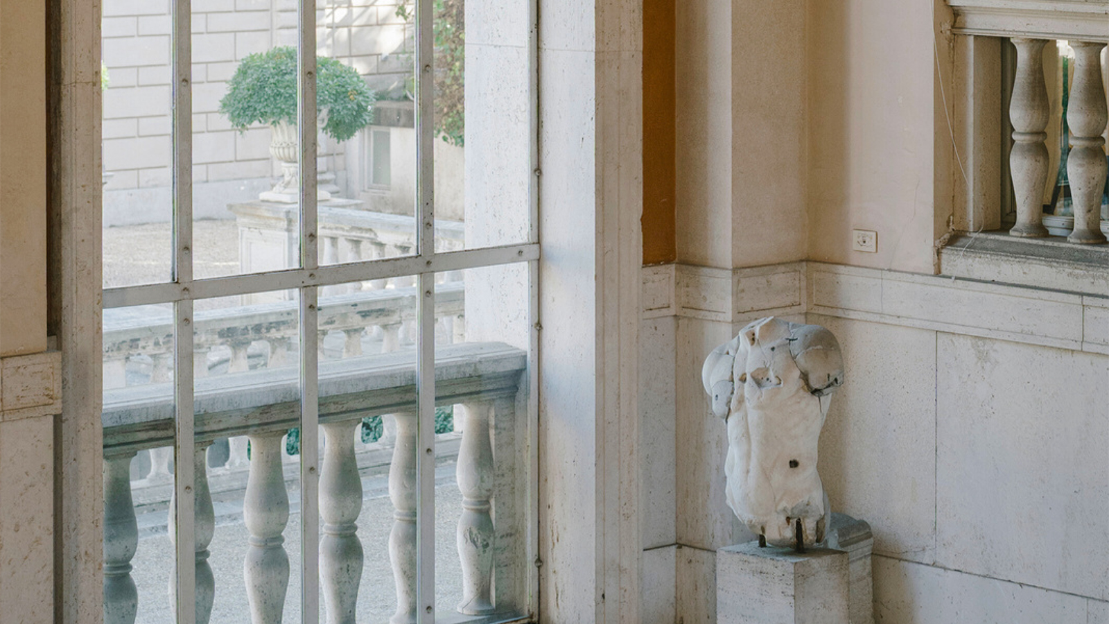 Color photograph of an atrium in a Roman building, with a window looking outide and a carved marble torso