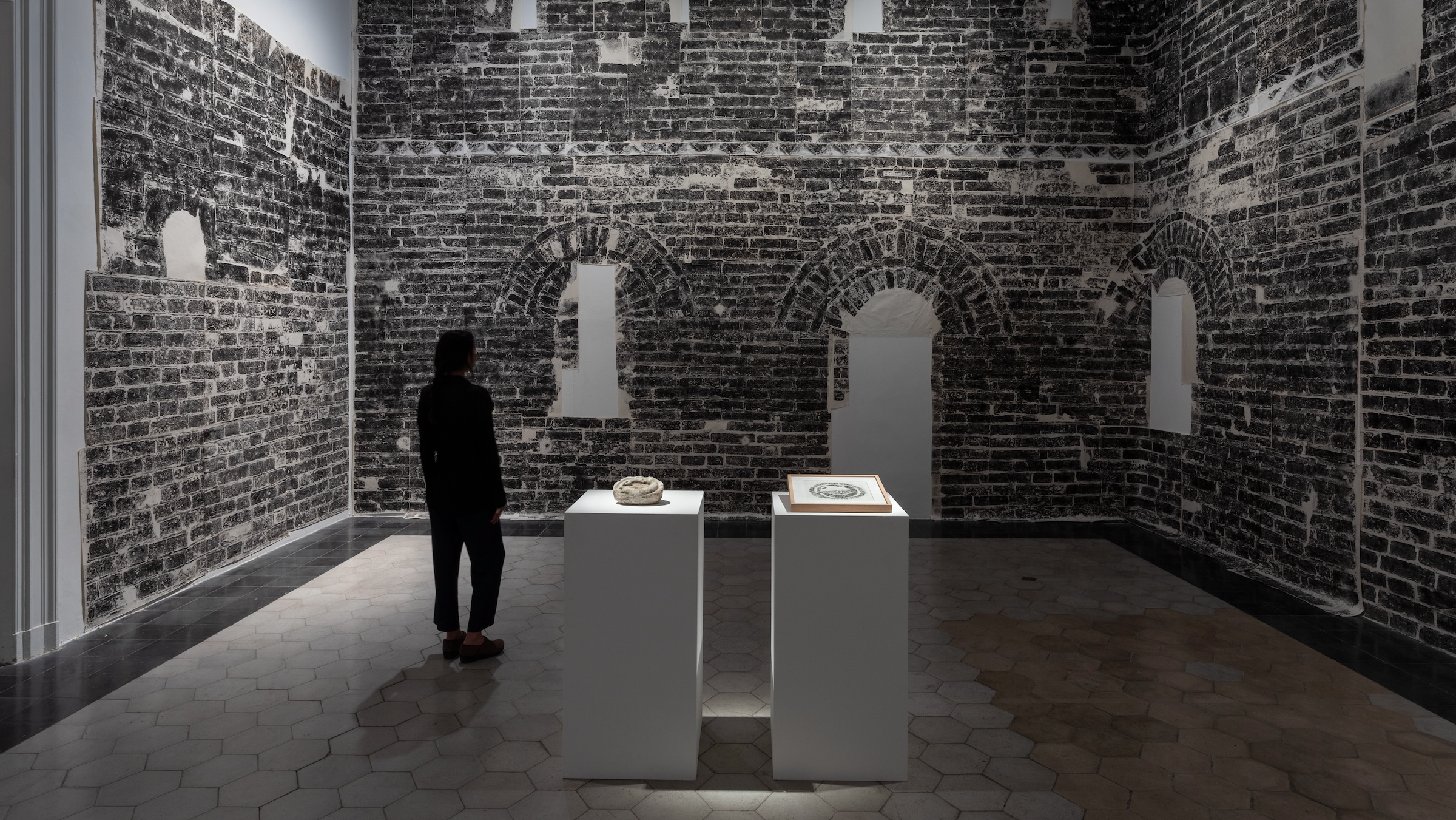 A woman stands in a gallery with a print of the Great Wall of China surrounding her