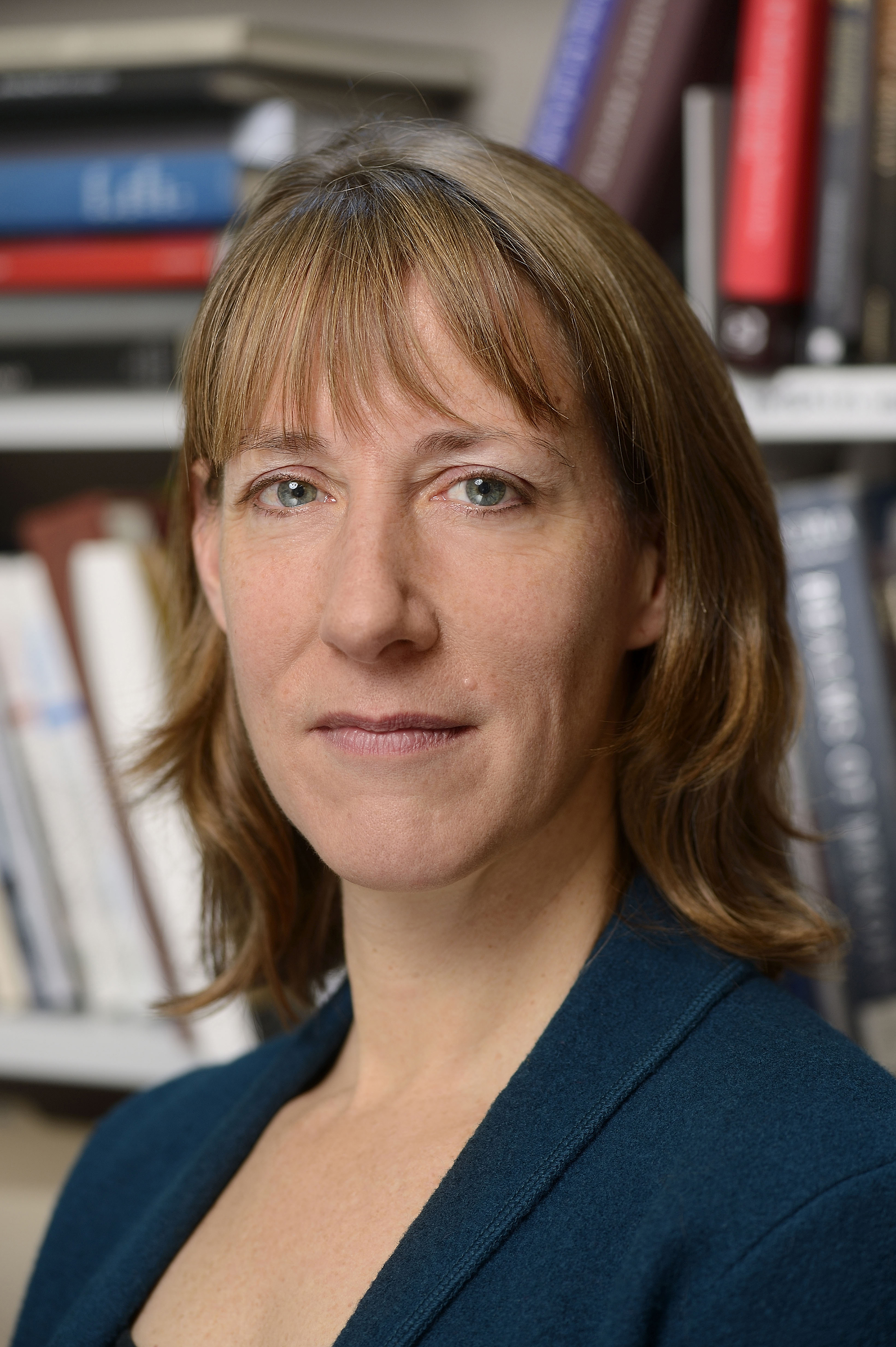 Color portrait of the head and shoulders of Elizabeth Rodini, facing forward and standing in front of a bookshelf