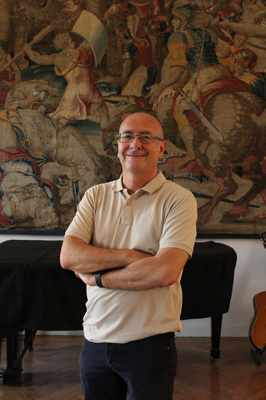Color photo of a light skinned man standing in front of a tapestry