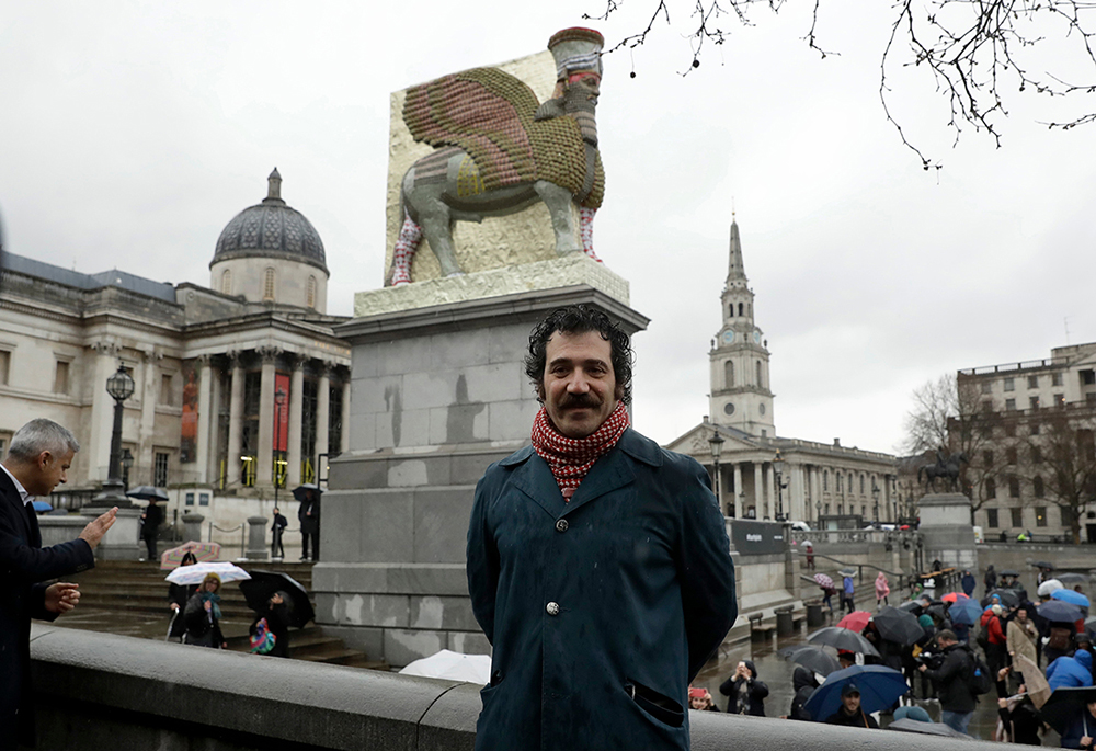 Color photograph of Michael Rakowitz standing in front of his sculpture on the Fourth Plinth in Trafalgar Square in London