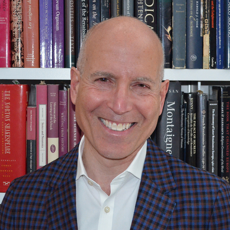 Peter N. Miller Color photograph of the head and torso of a light skinned man in front of a bookcase smiling at the camera