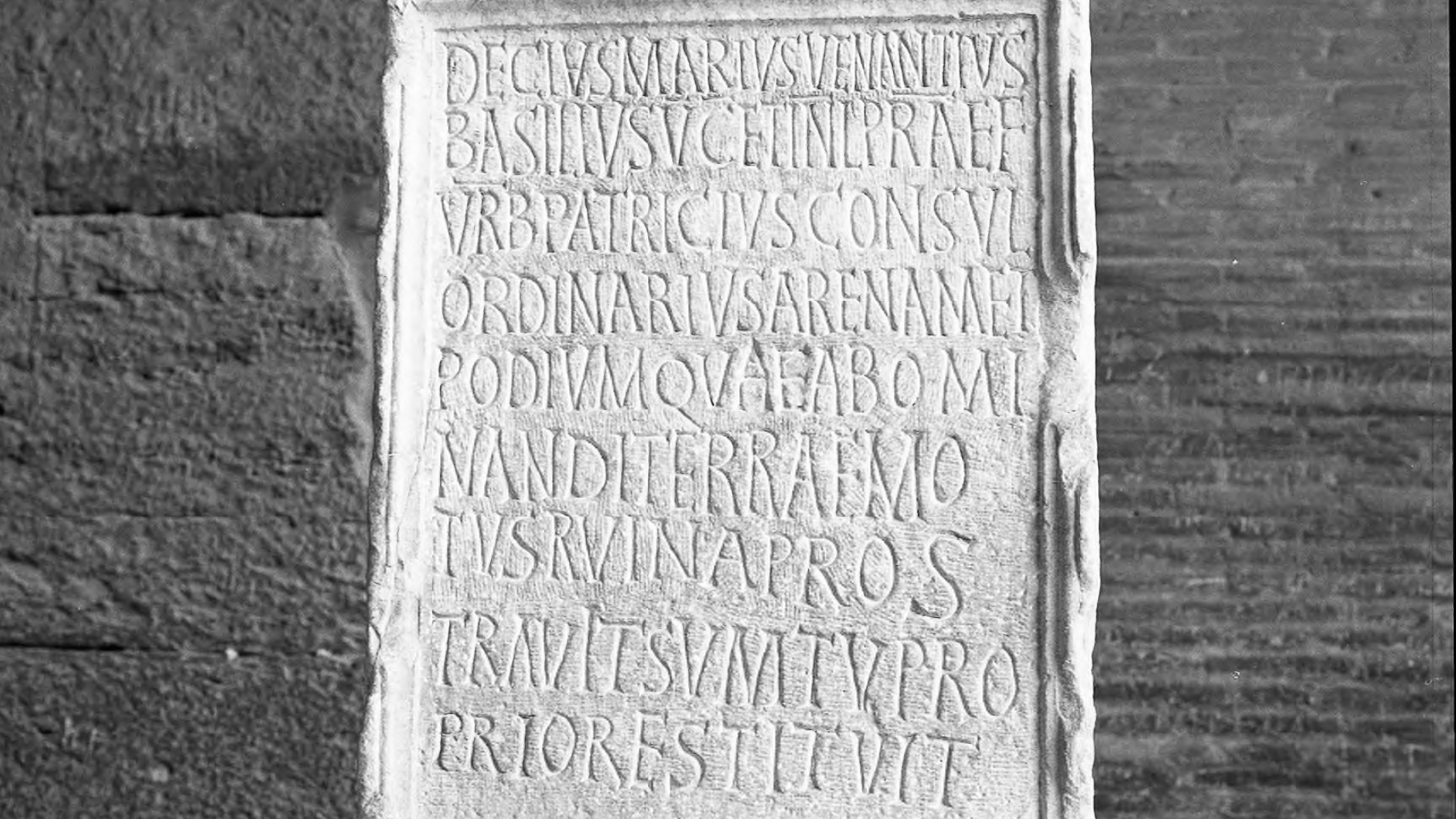 Black and white photograph of a rectangular vertically oriented memorial stone with nine lines of inscribed characters that form a dedication to D. M. Venantius Basilius