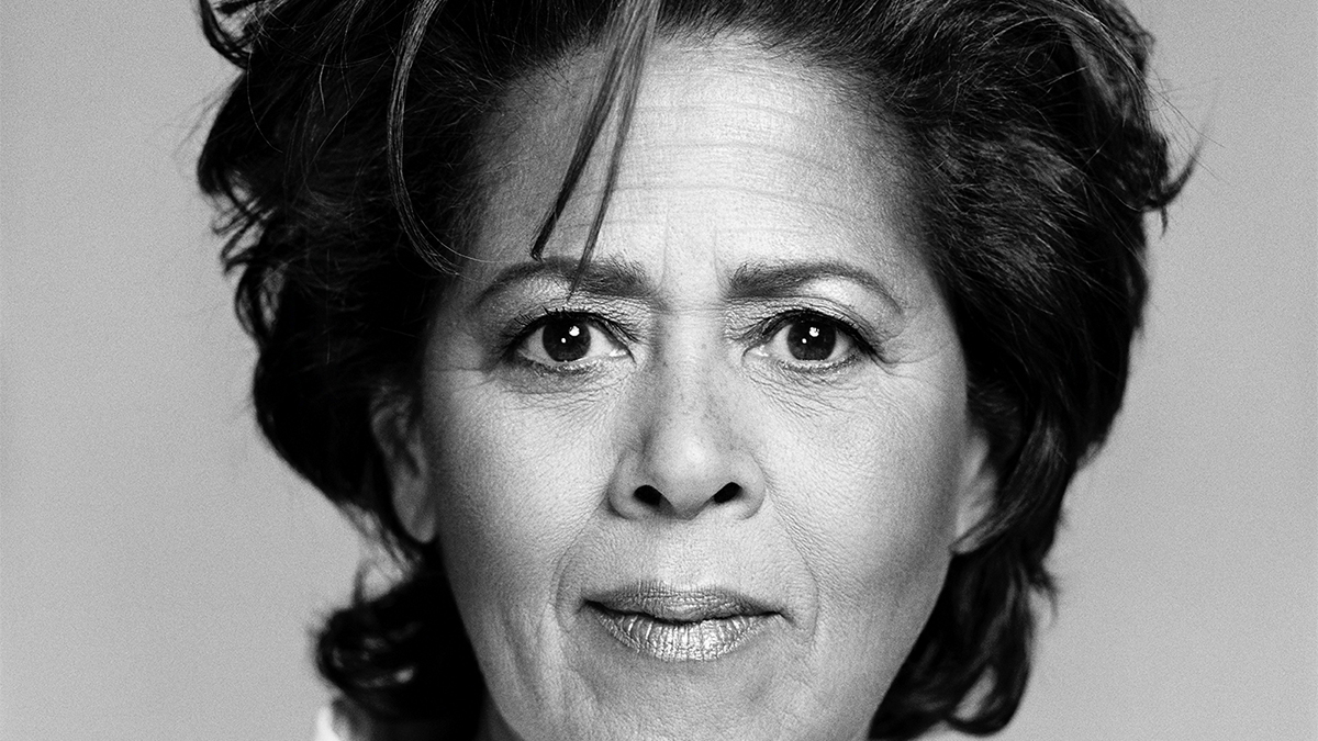 Black and white photograph of the face of a dark skinned woman looking directly at the camera