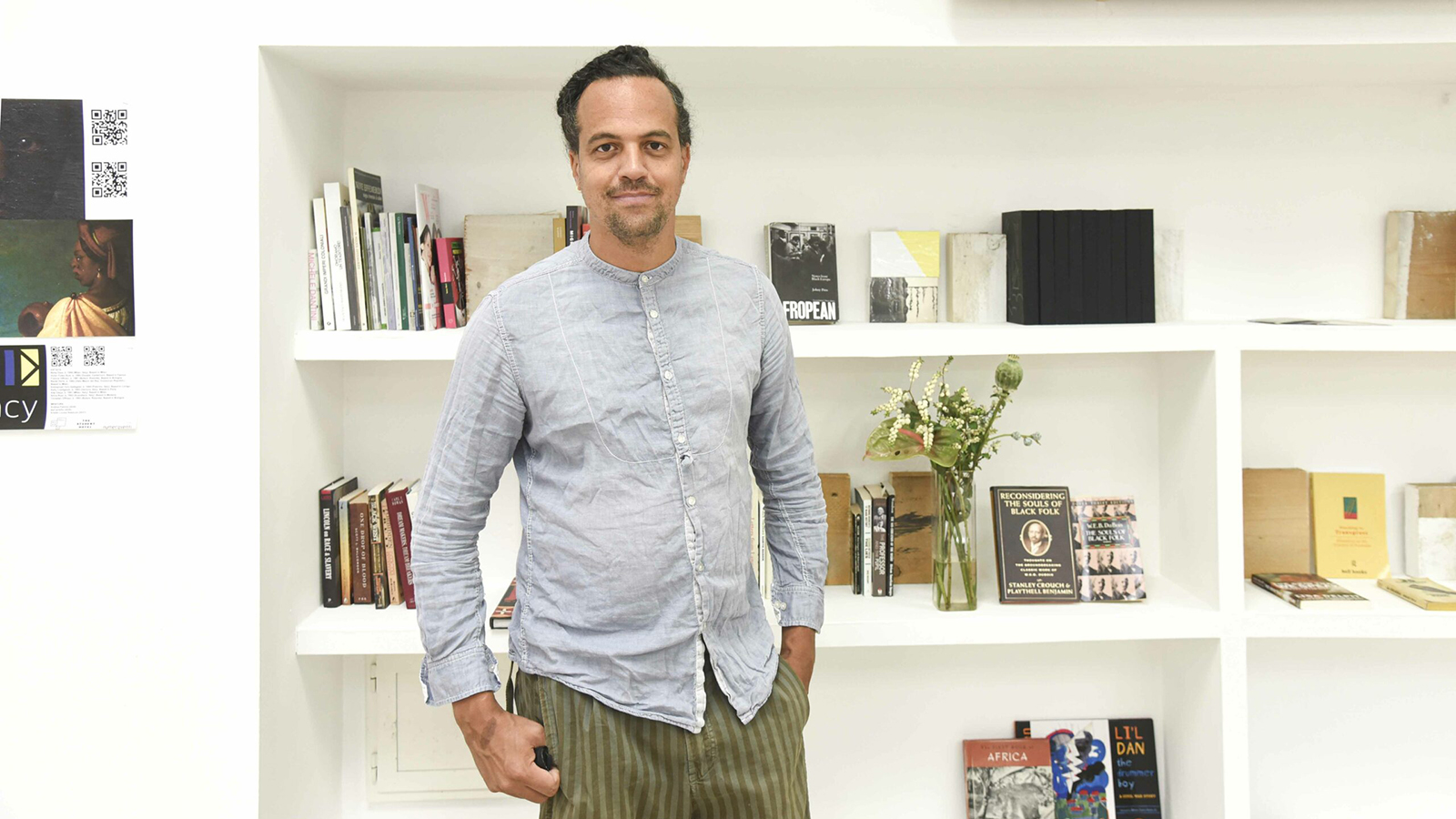 Color photograph of Justin Randolph Thompson standing in front of a bookshelf inside the Black History Month Florence office