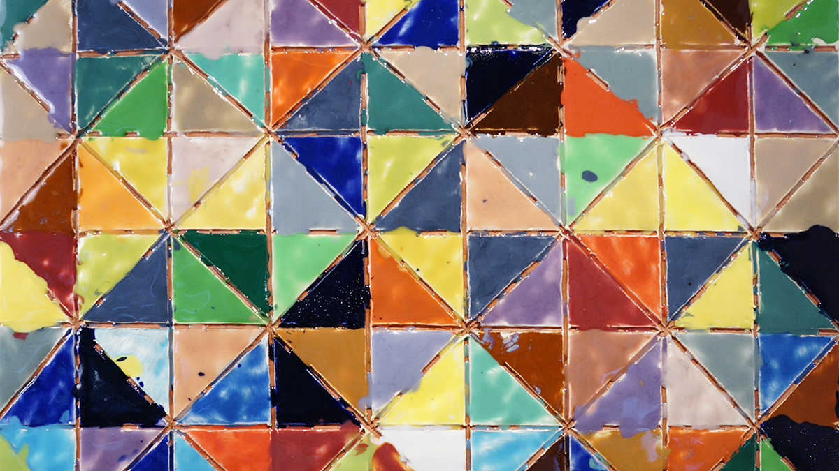 Detail of a flat ceramic artwork titled &quot;Pennsylvania Diamond Quilt&quot; that consists of dozens of triangle shapes in terracotta individually painted with glazes of many different colors