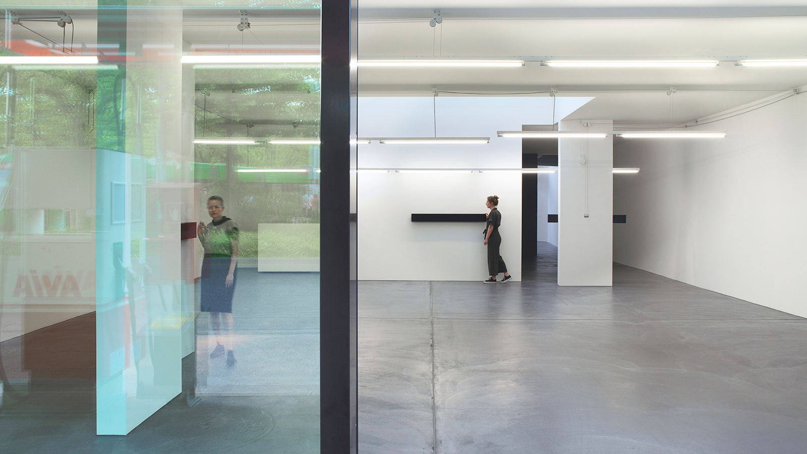 Far Afield - Sarah Oppenheimer Color photograph of an architectural art installation in a white cube gallery, with two light skinned women visible in the room
