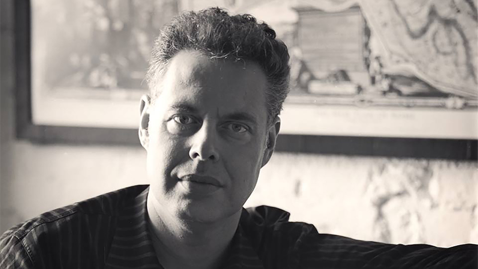 moody black and white photo of the head and shoulders of a light skinned man looking at the camera