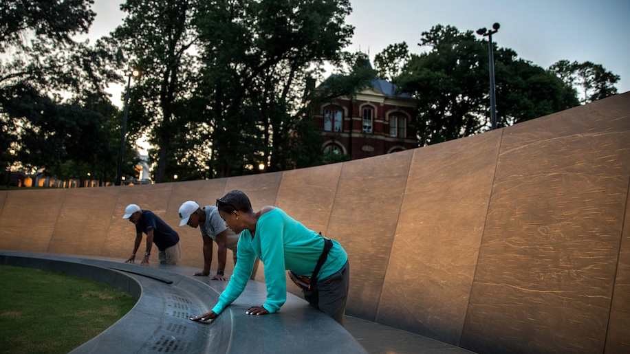 Color photograph of three women interacting with the Memorial to Enslaved Laborers